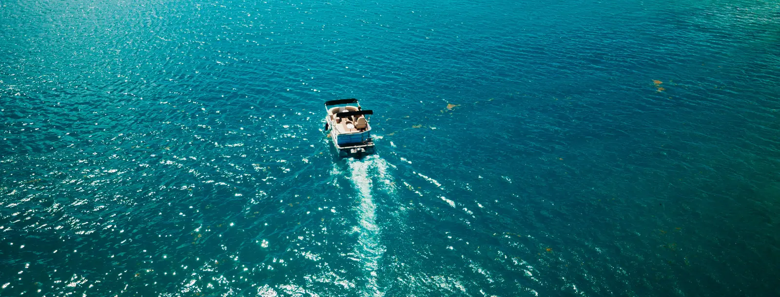 Un ponton Lounge Cruise en navigation dans une baie turquoise, vu du ciel