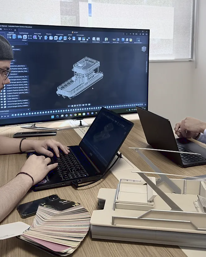 Écran de conception affichant le modèle 3D d'un ponton, devant sa maquette imprimée et un nuancier de sellerie
